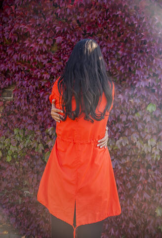 Woman hugging herself, rear view stock photo