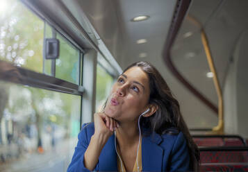 Junge Frau hört mit Kopfhörern Musik in einem Bus - AJOF00124