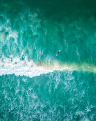 Luftaufnahme eines einsamen Surfers über aufgewühltem blauem Wasser, Kapstadt, Südafrika. - AAEF06311