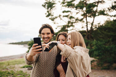 Glückliche Freunde nehmen Selfie auf Smartphone am Strand - MASF16086