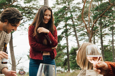 Cheerful woman talking with friends enjoying drinks in back yard - MASF16096