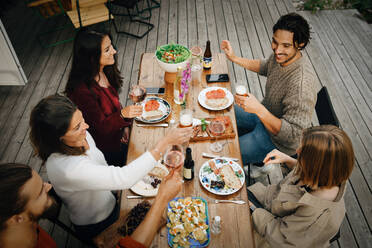 High angle view of friends enjoying drinks while having food during garden party - MASF16149