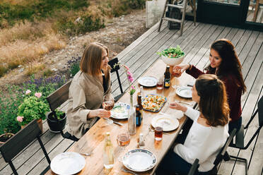 Hohe Winkel Ansicht der weiblichen Freunde im Gespräch beim Genießen Mahlzeit im Vorgarten - MASF16153