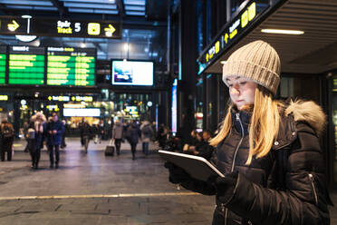 Teenager-Mädchen, das ein digitales Tablet benutzt, während es im Winter in der Stadt steht - MASF16154