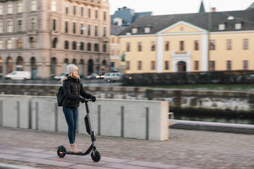 In voller Länge von Teenager-Mädchen fahren E-Scooter auf der Straße in der Stadt - MASF16158