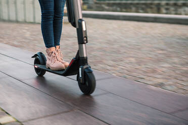 Low section of teenage girl riding on electric push scooter on street - MASF16163