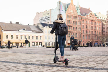 In voller Länge von Teenager-Mädchen Reiten elektrische Push-Roller auf der Straße in der Stadt - MASF16169