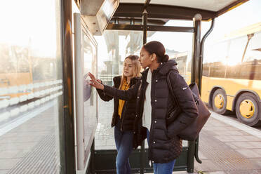 Freunde lesen eine Karte, während sie an einer Bushaltestelle in der Stadt stehen - MASF16176