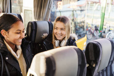 Lächelnde Freundinnen, die zusammen in einem Bus in der Stadt unterwegs sind - MASF16186