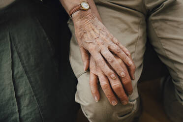 Midsection of retired senior couple holding hands sitting at nursing home - MASF16199