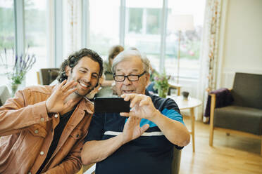 Senior man and grandson video conferencing on smart phone at elderly nursing home - MASF16222