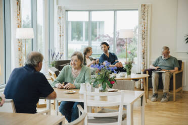 Ältere Männer und Frauen im Ruhestand sitzen mit einem Pfleger in einem Altenpflegeheim - MASF16252