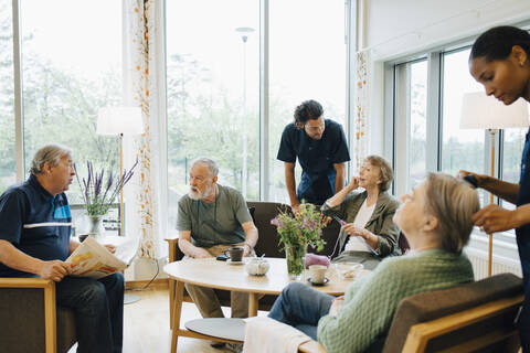 Männliche und weibliche Krankenschwestern, die sich im Pflegeheim um ältere Menschen im Ruhestand kümmern, lizenzfreies Stockfoto