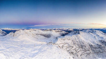 Drohnen-Panorama des Sonnenaufgangs über den engen Kurven der verschneiten Stilfserjoch-Bergstraße, Bormio, Valtellina, Lombardei, Italien, Europa - RHPLF13600