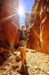 Unbekümmerte Touristin, die die malerische natürliche Schlucht von Standley Chasm genießt, während die Mittagssonne auf die spektakuläre Schlucht trifft, West MacDonnell National Park, Outback Red Centre, Northern Territory, Australien, Pazifik - RHPLF13702