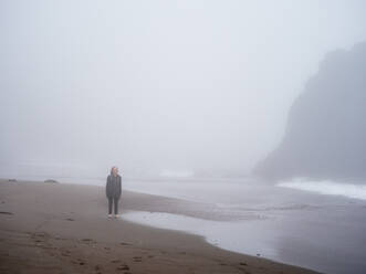 Tween steht allein an einem Strand im Nebel - CAVF72580