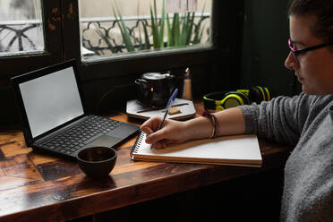 Young student is studying in a coffee shop with her laptop - CAVF72613