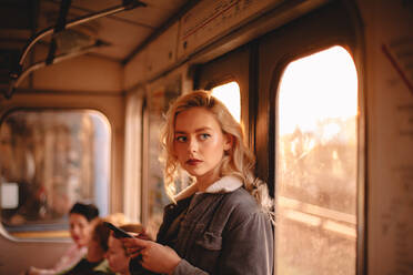 Junge Frau benutzt ihr Smartphone während der Fahrt in der U-Bahn - CAVF72617
