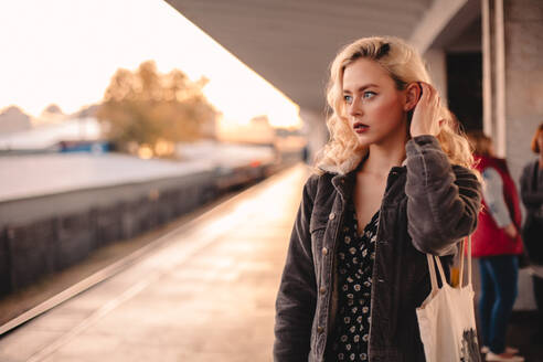Nachdenkliche junge Frau, die in einer U-Bahn-Station auf einen Zug wartet - CAVF72641