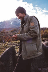 Happy hiker in mountains checking his phone - CAVF72668