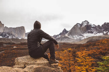 Wanderer auf Stein sitzend in den Bergen im Herbst - CAVF72725