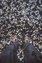 Unrecognizable person standing on wet pebbles - CAVF72729