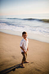 Junger Junge am Strand stehend bei Sonnenuntergang - CAVF72737