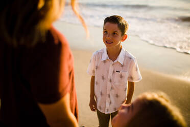 Son Smiles at Mom While Standing on Beach at Sunset - CAVF72740