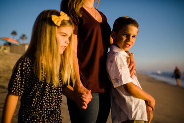 Mother Standing with Children on Beach at Sunset - CAVF72741