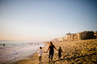 Mom Holding Hands with Children While Walking on Beach at Sunset - CAVF72743