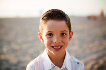 Young Boy Smiling at Camera on Beach at Sunset - CAVF72744