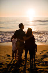 Vierköpfige Familie am Strand stehend, Blick auf den Ozean bei Sonnenuntergang - CAVF72748
