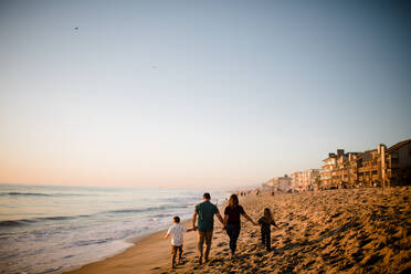 Family of Four Walking Away on Beach, Holding Hands at Sunset - CAVF72751