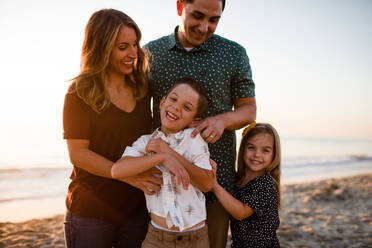 Family of Four Playing & Smiling on Beach at Sunset - CAVF72754