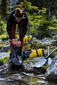 Eine Frau packt ihre Ausrüstung aus, um sich auf die Packwanderung über den Cirque Lake vorzubereiten. - CAVF72770