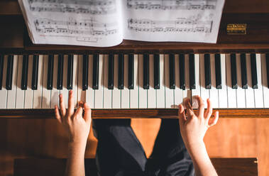 Top view of child's hands playing piano. - CAVF72814