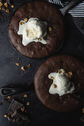 Nahaufnahme von Brownies mit Eis und Nüssen in gusseisernen Bratpfannen. - CAVF72821