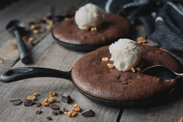 Nahaufnahme von Brownies mit Eis und Nüssen in gusseisernen Bratpfannen. - CAVF72824