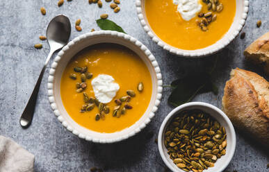 Draufsicht auf Schalen mit Butternusskürbissuppe auf grauem Hintergrund. - CAVF72831