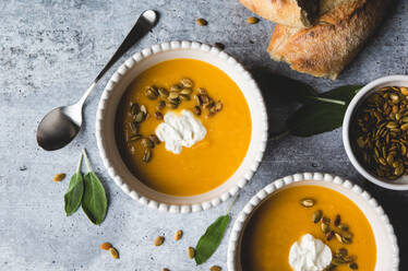 Nahaufnahme von Schüsseln mit Butternusskürbissuppe auf grauem Hintergrund. - CAVF72832