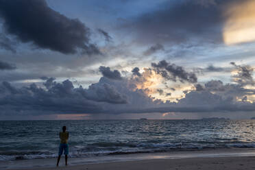 Eine Reisende beobachtet den Sonnenuntergang an einem Strand der Insel Koh Lanta, Thailand. - CAVF72838