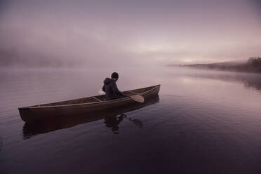 Solo paddling on a misty pond at sunrise. - CAVF72873