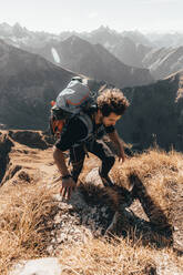 Junger Wanderer auf steilem Pfad vor alpinem Hintergrund - CAVF72885