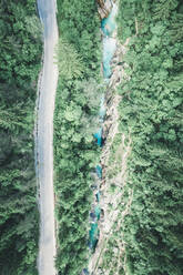 Luftaufnahme einer Autobahn durch den Wald neben dem türkisblauen Fluss - CAVF72894