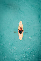 Medium framed shot from above of kayaker in teal water - CAVF72897