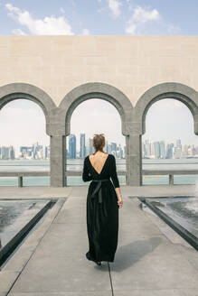 Rückenansicht einer jungen Frau, die in Doha spazieren geht und auf das Meer schaut - CAVF72914