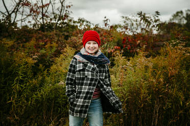 Teen Girl in Red Hat Standing in einem Herbst farbigen Feld lächelnd - CAVF72922