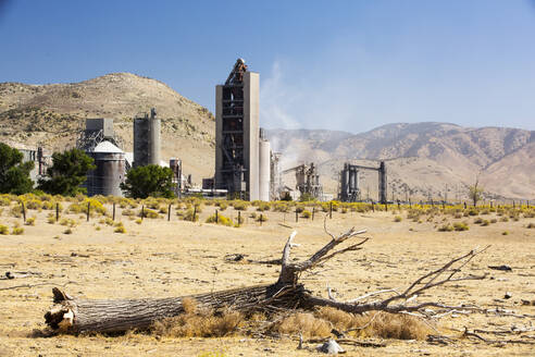 Ein Zementwerk am Tehachapi Pass in Kalifornien, USA, mit dürregeschädigten Bäumen im Vordergrund. Die Zementherstellung ist eine der kohlenstoffhungrigsten Industrien der Welt und trägt zur Klimaveränderung bei - CAVF72938