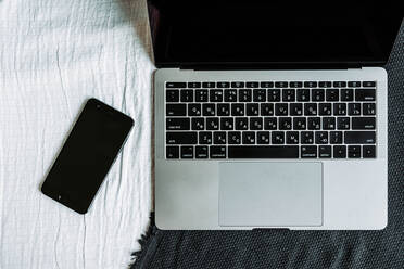 Black phone and laptop on the sofa - CAVF72985