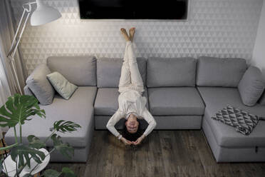 Frau entspannt sich kopfüber auf der Couch - KMKF01178